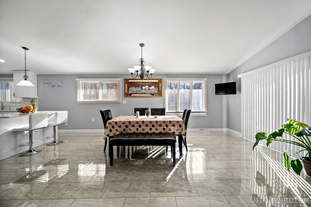 dining space with sink, a chandelier, and vaulted ceiling