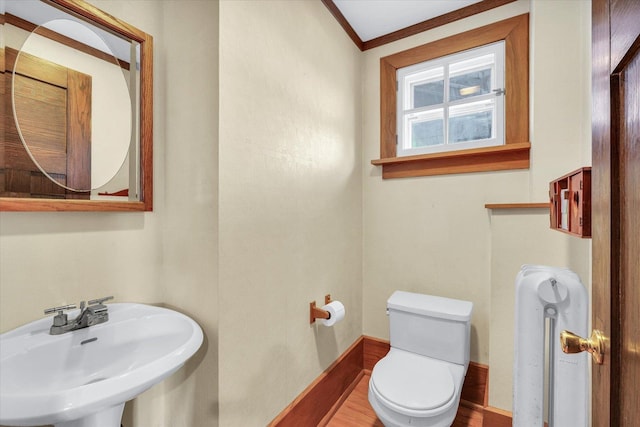 bathroom with crown molding, wood-type flooring, toilet, and sink