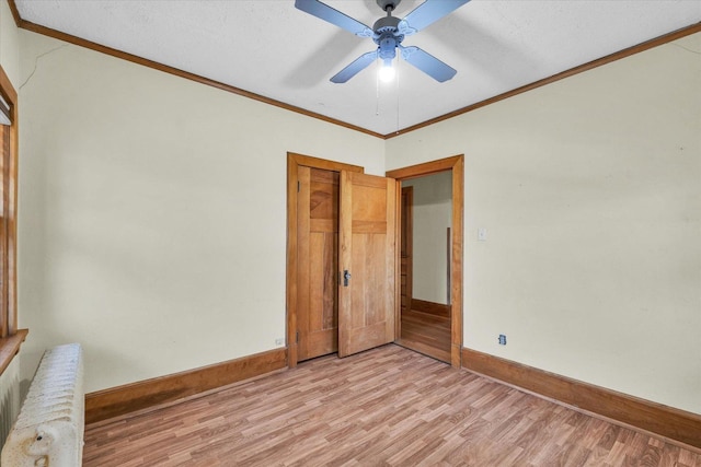 unfurnished bedroom featuring radiator, ornamental molding, ceiling fan, light wood-type flooring, and a closet