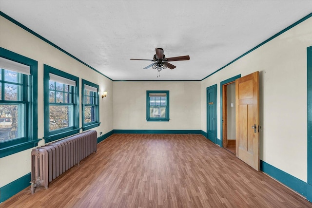 unfurnished room featuring ceiling fan, hardwood / wood-style floors, radiator heating unit, ornamental molding, and a textured ceiling