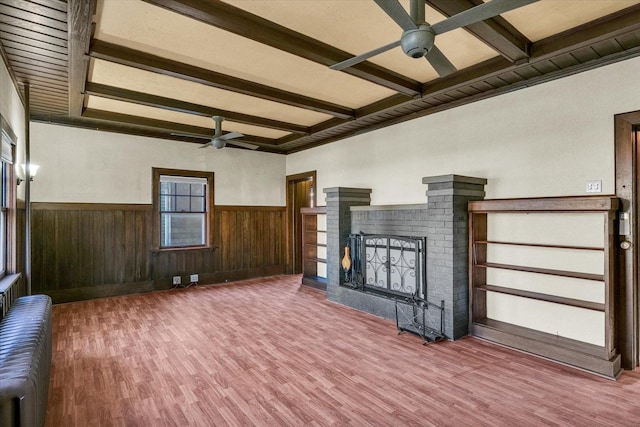 unfurnished living room featuring a brick fireplace, radiator, ceiling fan, beam ceiling, and hardwood / wood-style floors