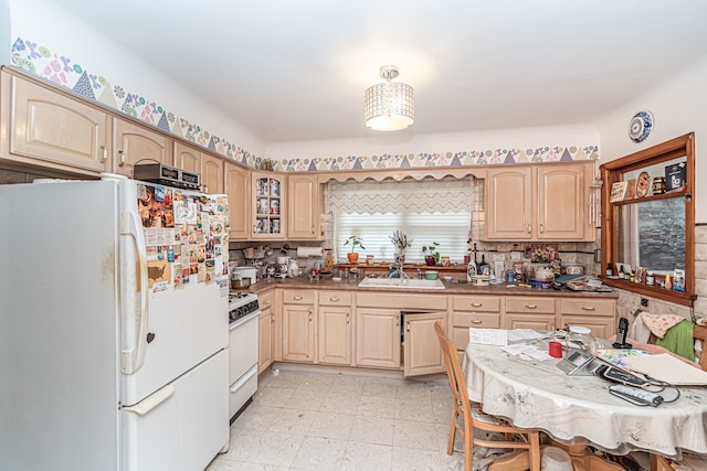 kitchen featuring light brown cabinets, white appliances, and sink