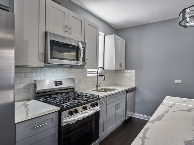 kitchen with light stone countertops, stainless steel appliances, dark hardwood / wood-style floors, and sink