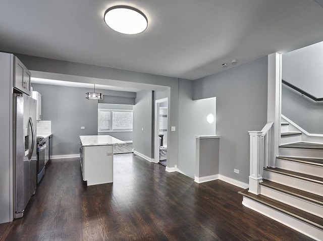 kitchen featuring stainless steel fridge, dark hardwood / wood-style flooring, a kitchen island, and decorative light fixtures