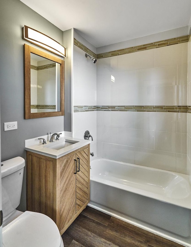 full bathroom with hardwood / wood-style flooring, vanity, toilet, and tiled shower / bath