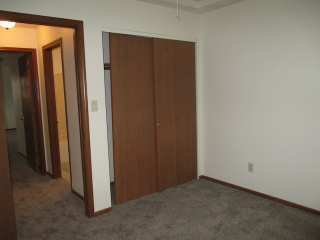 unfurnished bedroom with a closet and dark carpet