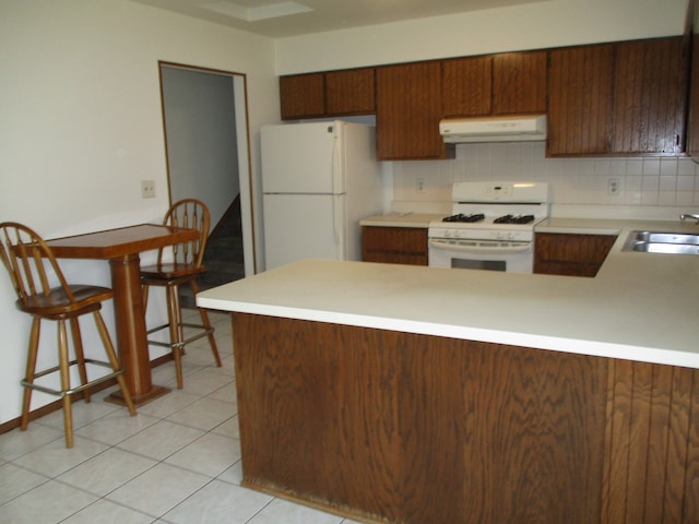 kitchen featuring white appliances, sink, light tile patterned floors, tasteful backsplash, and kitchen peninsula