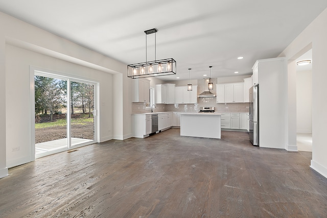 kitchen featuring wall chimney range hood, dark hardwood / wood-style floors, decorative light fixtures, a kitchen island, and white cabinetry