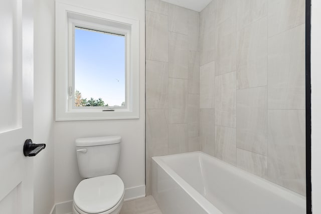 bathroom featuring tiled shower / bath combo and toilet