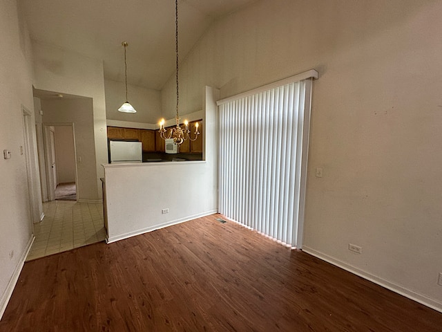 unfurnished living room featuring a chandelier, dark hardwood / wood-style floors, and high vaulted ceiling