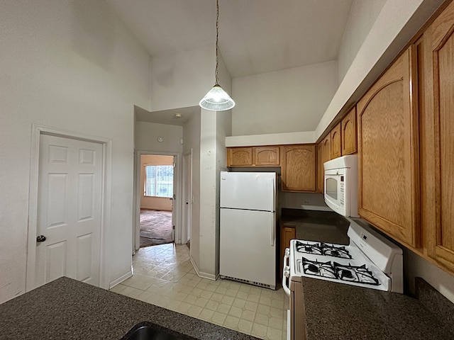 kitchen with white appliances, decorative light fixtures, and high vaulted ceiling