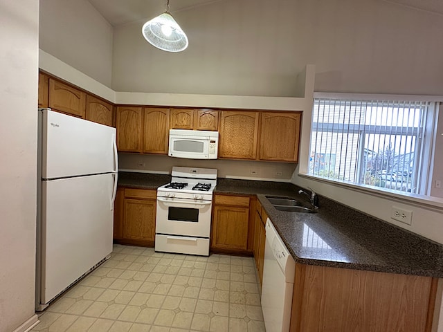 kitchen featuring a high ceiling, white appliances, hanging light fixtures, and sink