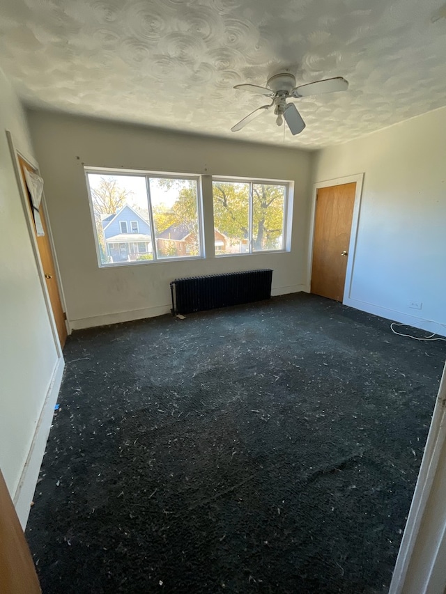 carpeted spare room featuring radiator and ceiling fan