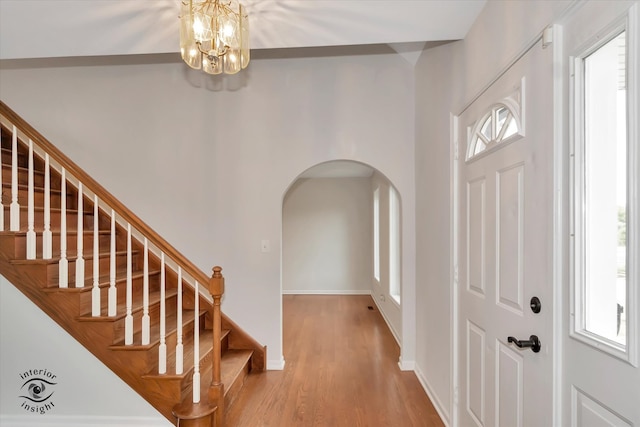 foyer entrance with hardwood / wood-style floors, a wealth of natural light, and a chandelier