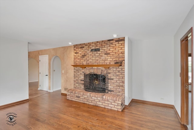 unfurnished living room with hardwood / wood-style floors and a brick fireplace