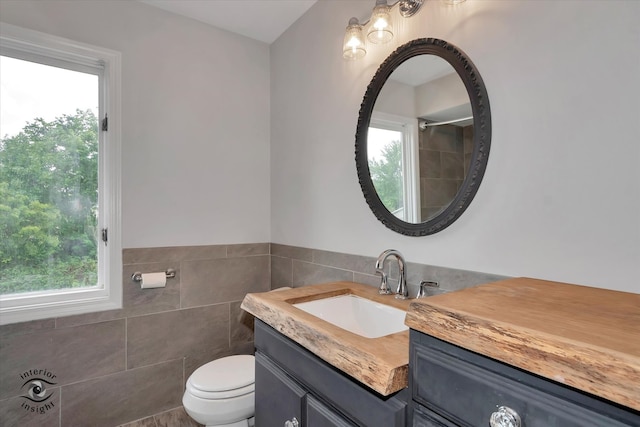 bathroom featuring vanity, toilet, tile walls, and a wealth of natural light