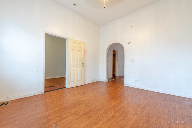 unfurnished room with light wood-type flooring and a high ceiling