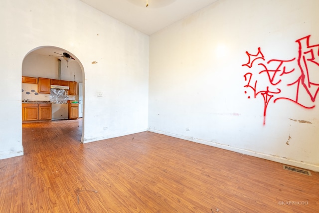 empty room featuring ceiling fan, light hardwood / wood-style floors, and high vaulted ceiling