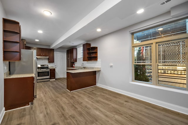 kitchen featuring decorative backsplash, appliances with stainless steel finishes, kitchen peninsula, and dark wood-type flooring