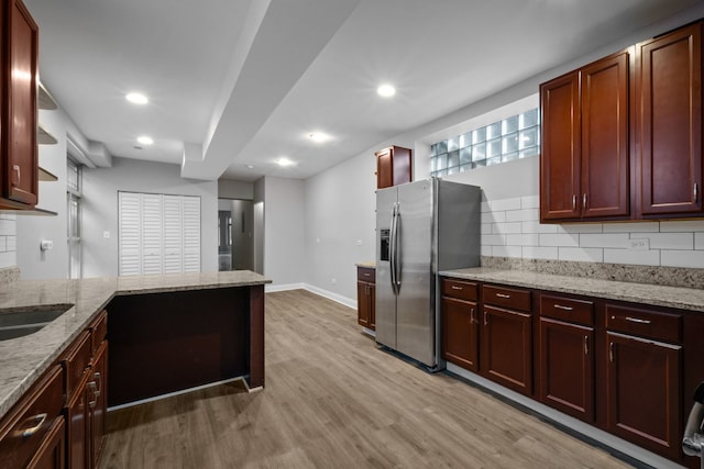 kitchen featuring stainless steel fridge, tasteful backsplash, light stone countertops, and light hardwood / wood-style flooring