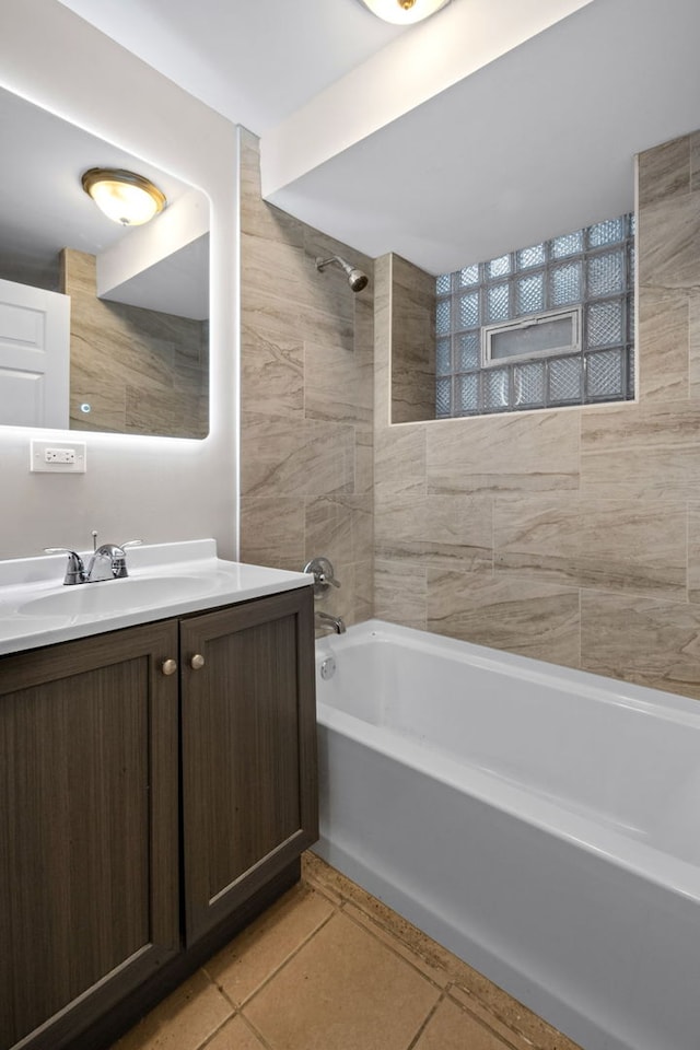 bathroom with tile patterned floors, tile walls, vanity, and tiled shower / bath combo