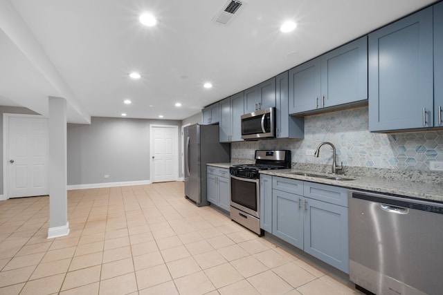 kitchen featuring sink, light stone countertops, tasteful backsplash, light tile patterned flooring, and stainless steel appliances