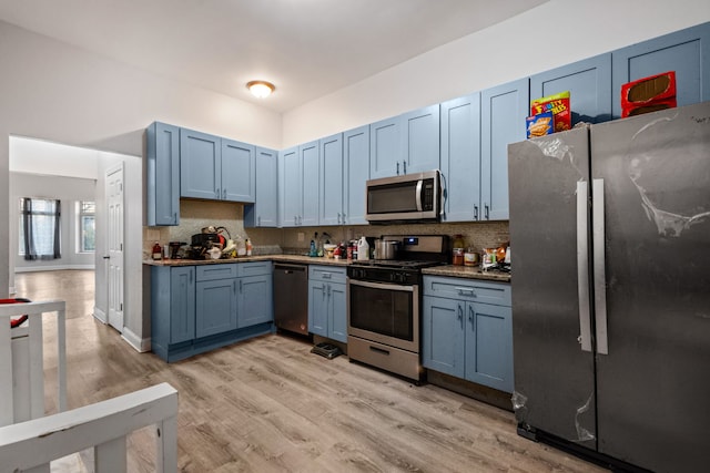 kitchen with light hardwood / wood-style floors, blue cabinets, backsplash, and appliances with stainless steel finishes