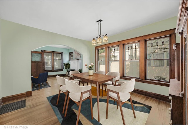 dining room featuring a brick fireplace, a chandelier, and light hardwood / wood-style flooring