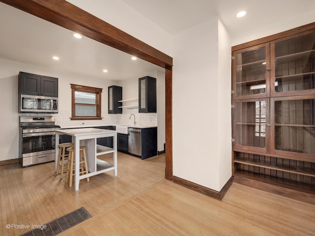 kitchen with a center island, a breakfast bar area, tasteful backsplash, light hardwood / wood-style floors, and stainless steel appliances