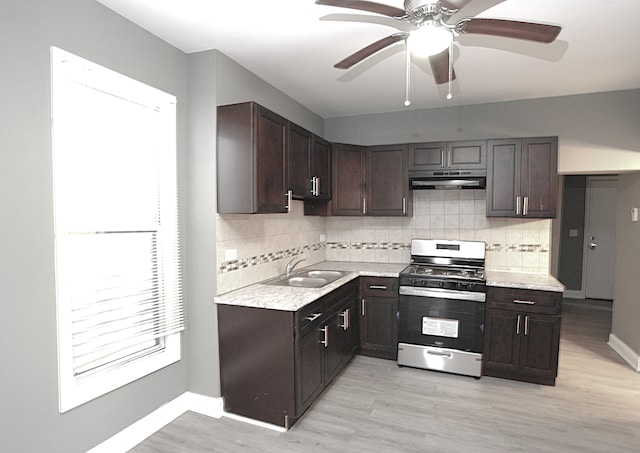 kitchen featuring tasteful backsplash, light hardwood / wood-style flooring, stainless steel gas range oven, and sink