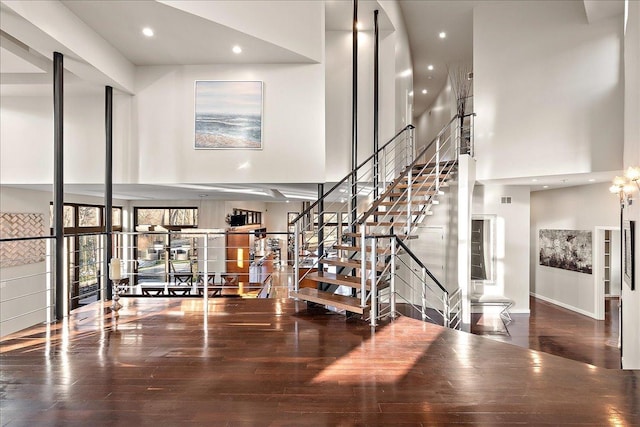 stairs with wood-type flooring and a high ceiling