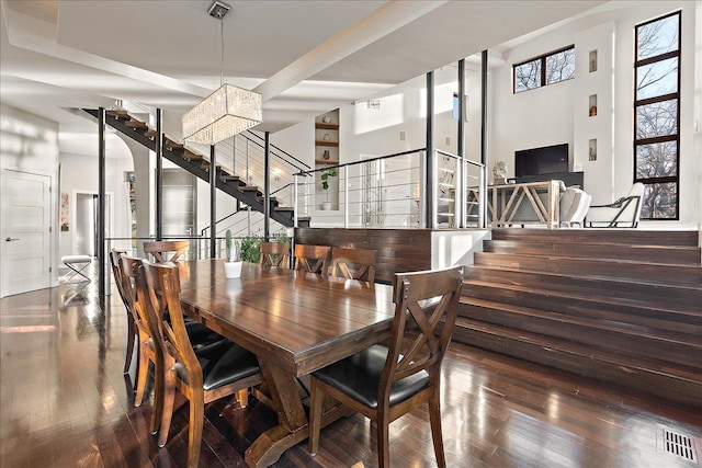 dining area with a towering ceiling, dark hardwood / wood-style floors, and a notable chandelier