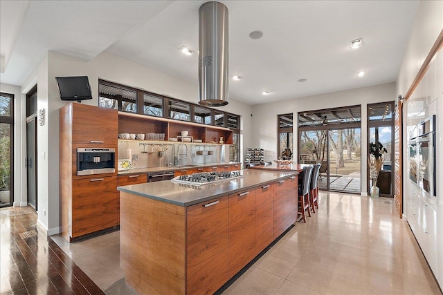 kitchen with a spacious island, sink, light wood-type flooring, appliances with stainless steel finishes, and stainless steel counters