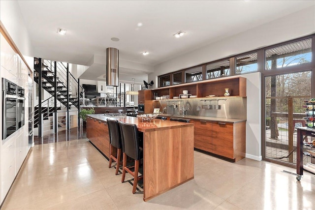 kitchen featuring a center island, wooden counters, oven, tasteful backsplash, and a kitchen bar