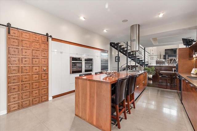 kitchen featuring a kitchen breakfast bar, a barn door, a kitchen island, and white cabinetry