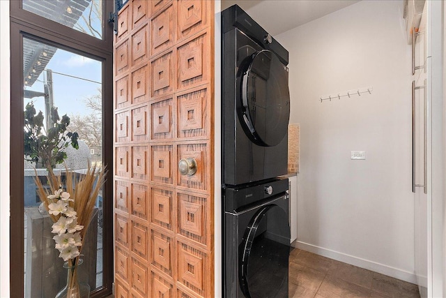 clothes washing area with stacked washer / dryer and dark tile patterned floors