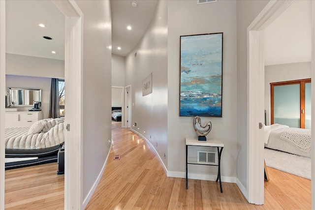 hall featuring light hardwood / wood-style floors and a towering ceiling