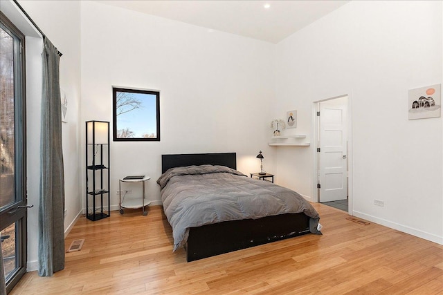 bedroom featuring a high ceiling and light hardwood / wood-style flooring