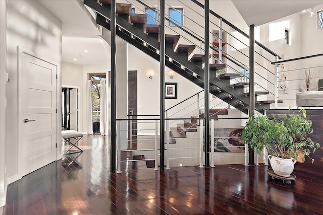 stairs featuring wood-type flooring and a high ceiling