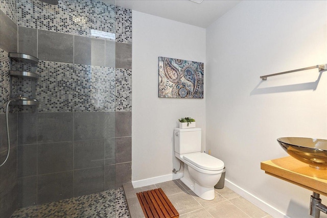 bathroom with a tile shower, tile patterned flooring, and toilet