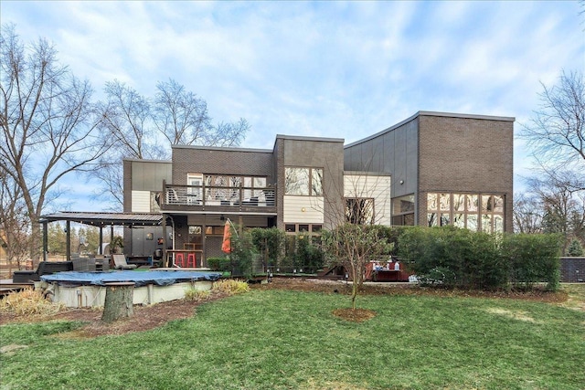 back of property featuring a yard, a balcony, and a covered pool