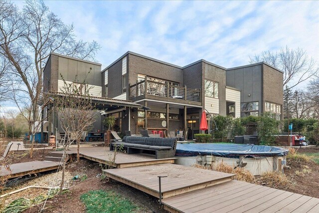 back of property featuring an outdoor hangout area, a balcony, and a covered pool