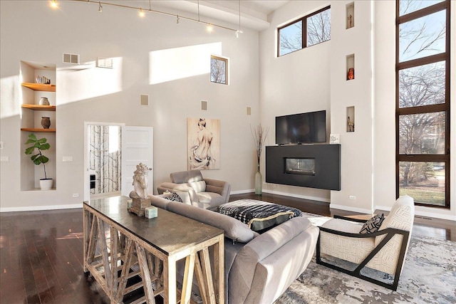 living room with beam ceiling, dark hardwood / wood-style flooring, and a high ceiling