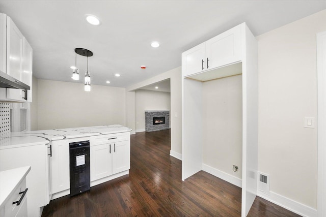 kitchen with dark wood-type flooring, white cabinetry, light stone counters, and decorative light fixtures