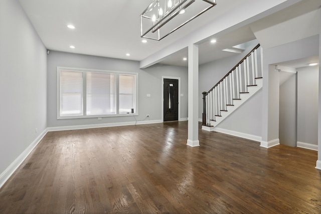 unfurnished living room with dark hardwood / wood-style flooring and a notable chandelier