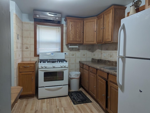 kitchen with decorative backsplash, sink, light hardwood / wood-style floors, and white appliances