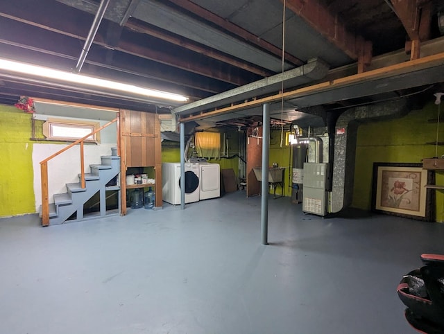 basement with gas water heater, heating unit, and washing machine and clothes dryer