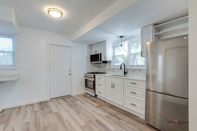 kitchen with sink, white cabinets, hanging light fixtures, and appliances with stainless steel finishes