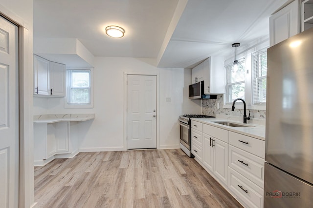 kitchen with sink, hanging light fixtures, stainless steel appliances, white cabinets, and light wood-type flooring