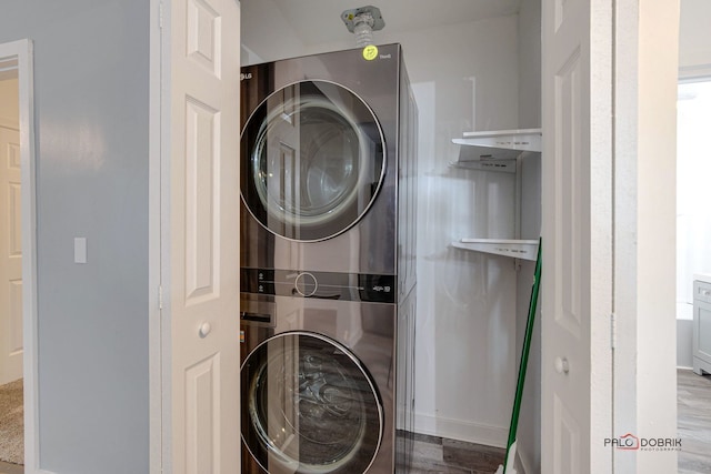 clothes washing area with light hardwood / wood-style floors and stacked washer / dryer